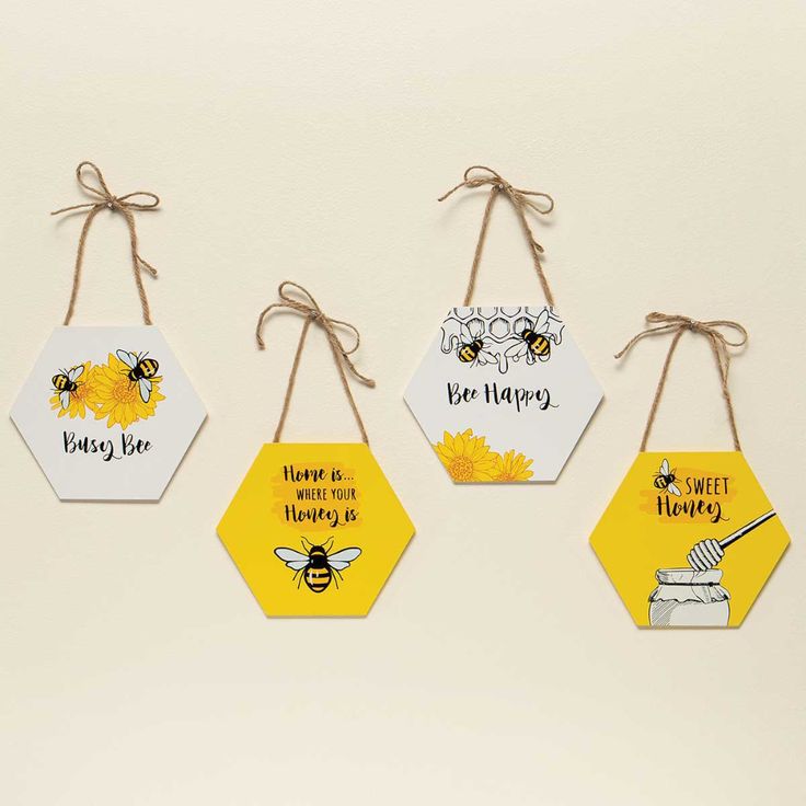 four hexagonal tags with bees and honey sayings hanging from twine strings