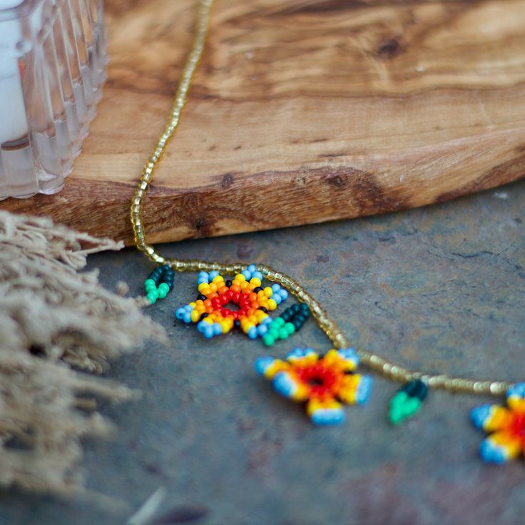 a colorful beaded necklace sitting on top of a wooden table next to a container