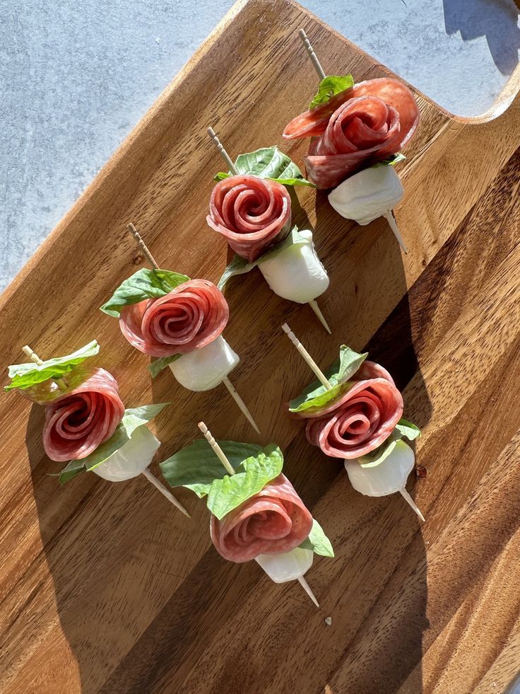 small appetizers with flowers are on a wooden cutting board, ready to be served