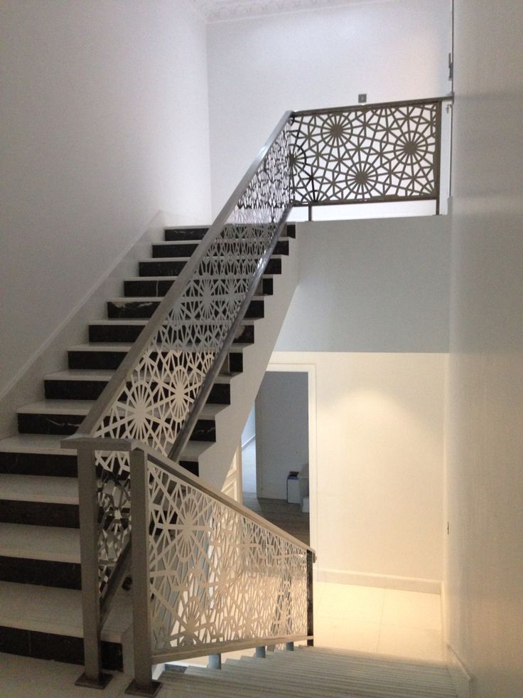 an iron stair railing with decorative design on the top and bottom handrails in a white room