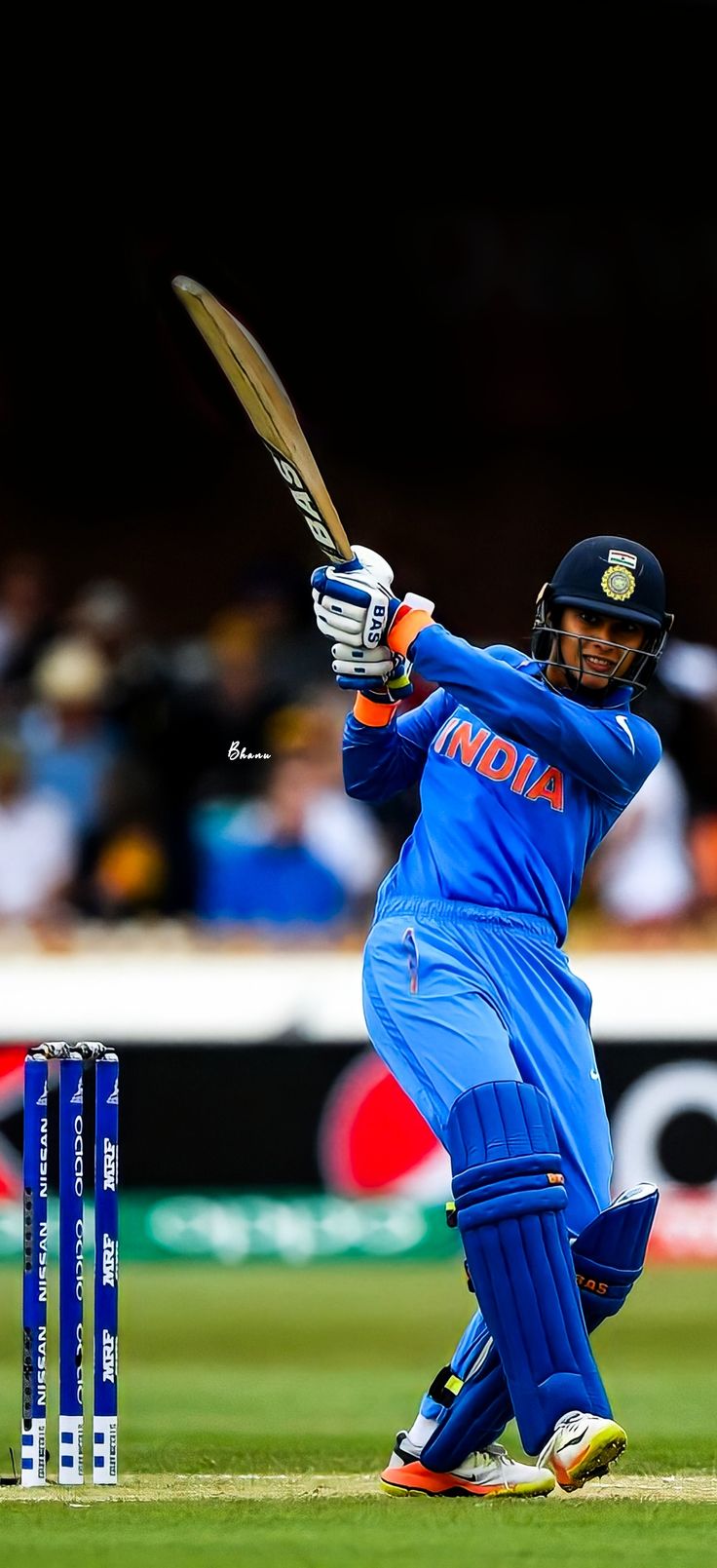 a man swinging a bat at a ball during a cricket game in front of a crowd