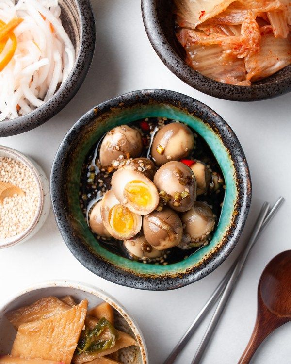 three bowls filled with food on top of a white table next to spoons and utensils