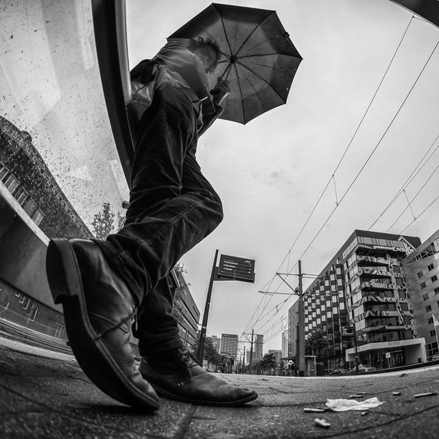 a man with an umbrella is leaning against a wall on the side of the street