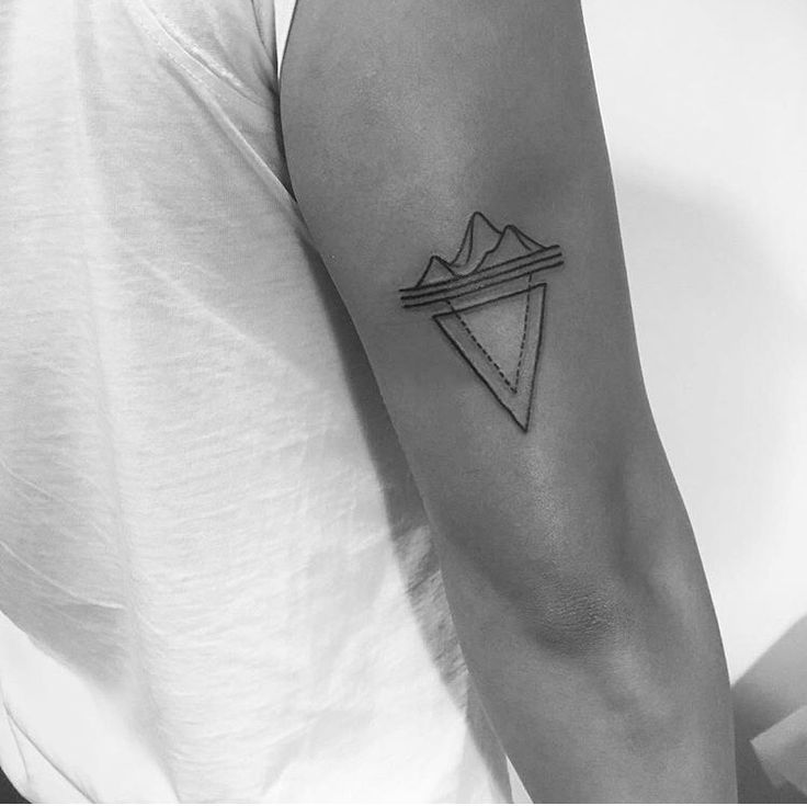 a black and white photo of a man's arm with a triangle tattoo on it