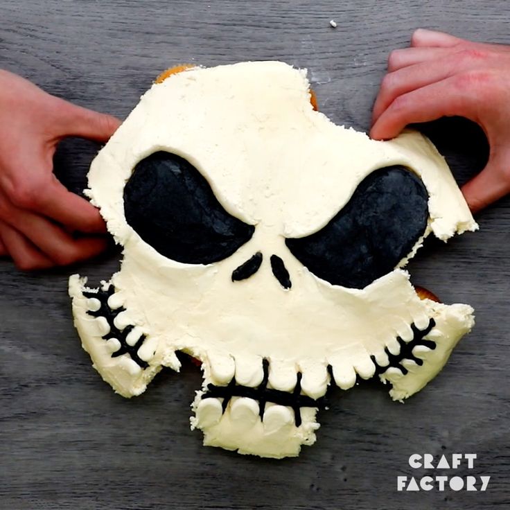 someone is decorating a skull cake with white frosting and black icing on it