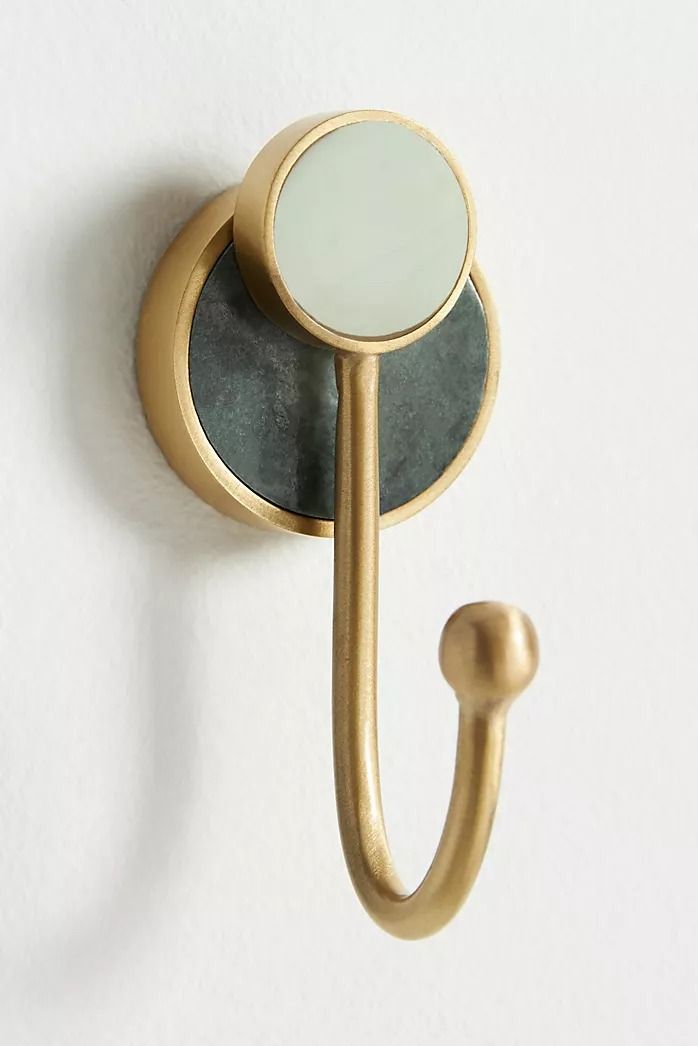 a mirror mounted to the side of a wall next to a hook on a white wall