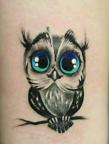 an owl tattoo with blue eyes on the arm