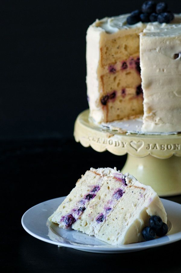 a slice of cake on a plate next to another piece of cake with blueberries