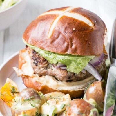 a hamburger with lettuce, tomato and other toppings on a white plate