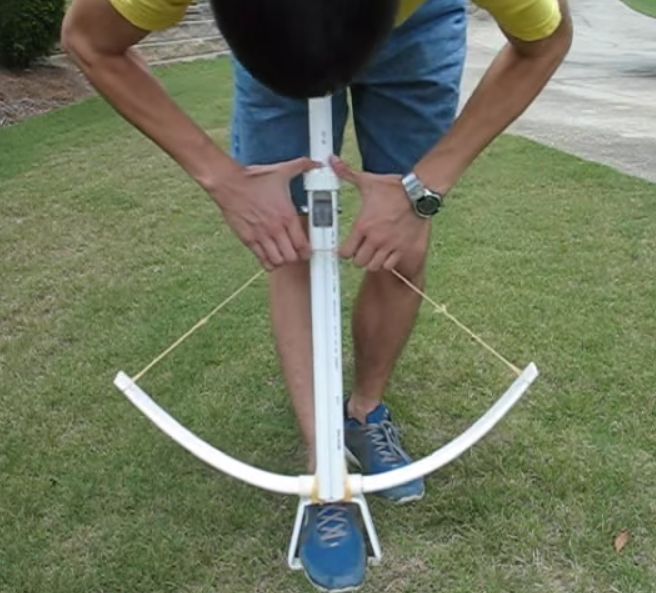 a man standing on top of a lawn holding onto an upside down pole with one hand