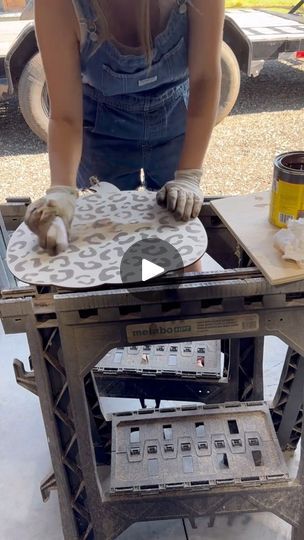 a woman in overalls and gloves working on a piece of metal with an ironing board