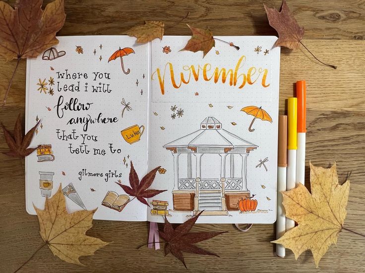 an open notebook with autumn leaves and writing on the pages, next to some pencils