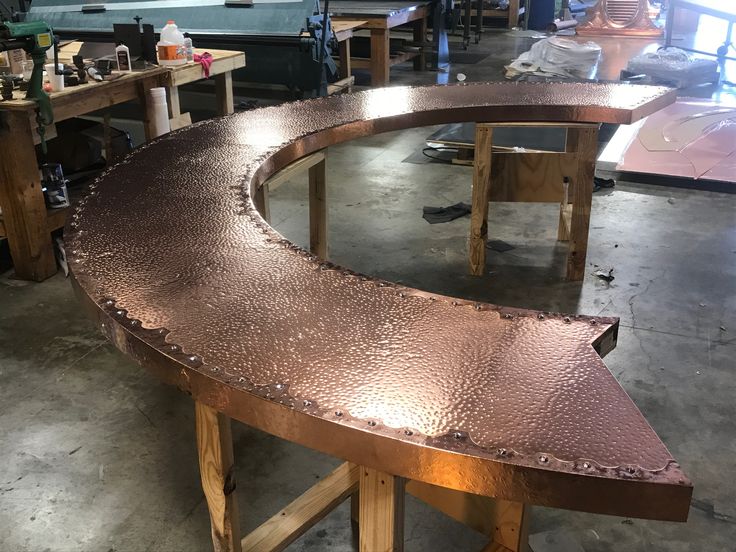 an oval metal table being worked on in a shop