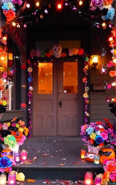 halloween decorations on the front steps of a house with candles and flowers in pots outside