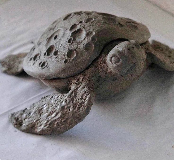 a clay turtle sitting on top of a piece of white paper with holes in it's shell