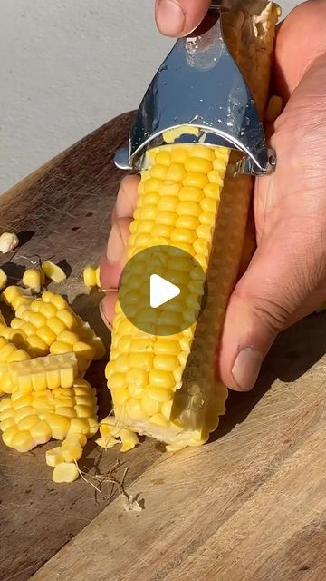 a person is cutting corn on the cob with a knife and some kernels