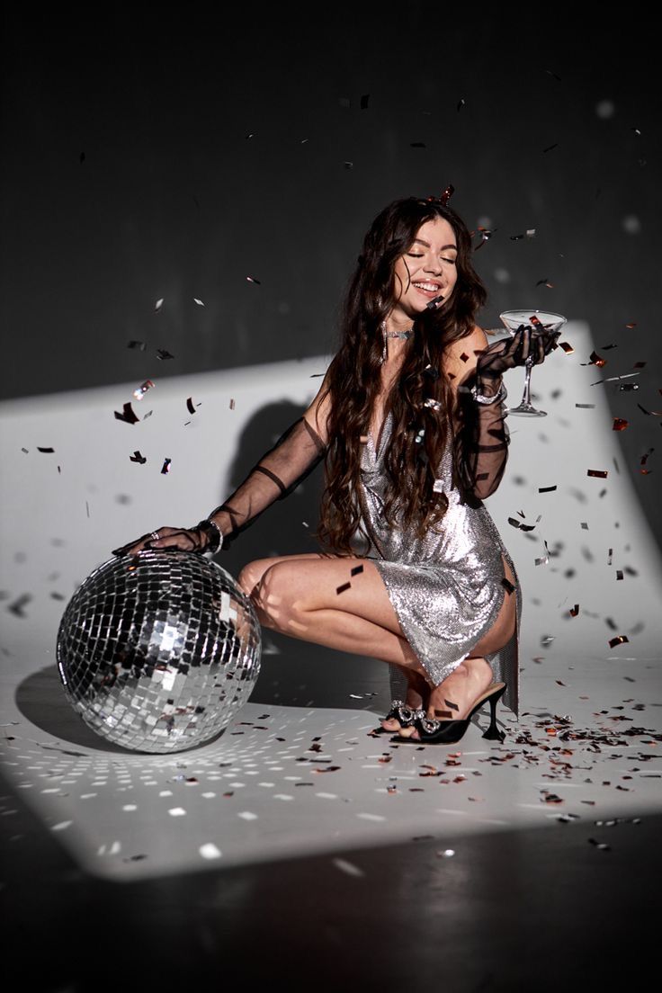 a woman kneeling down next to a disco ball