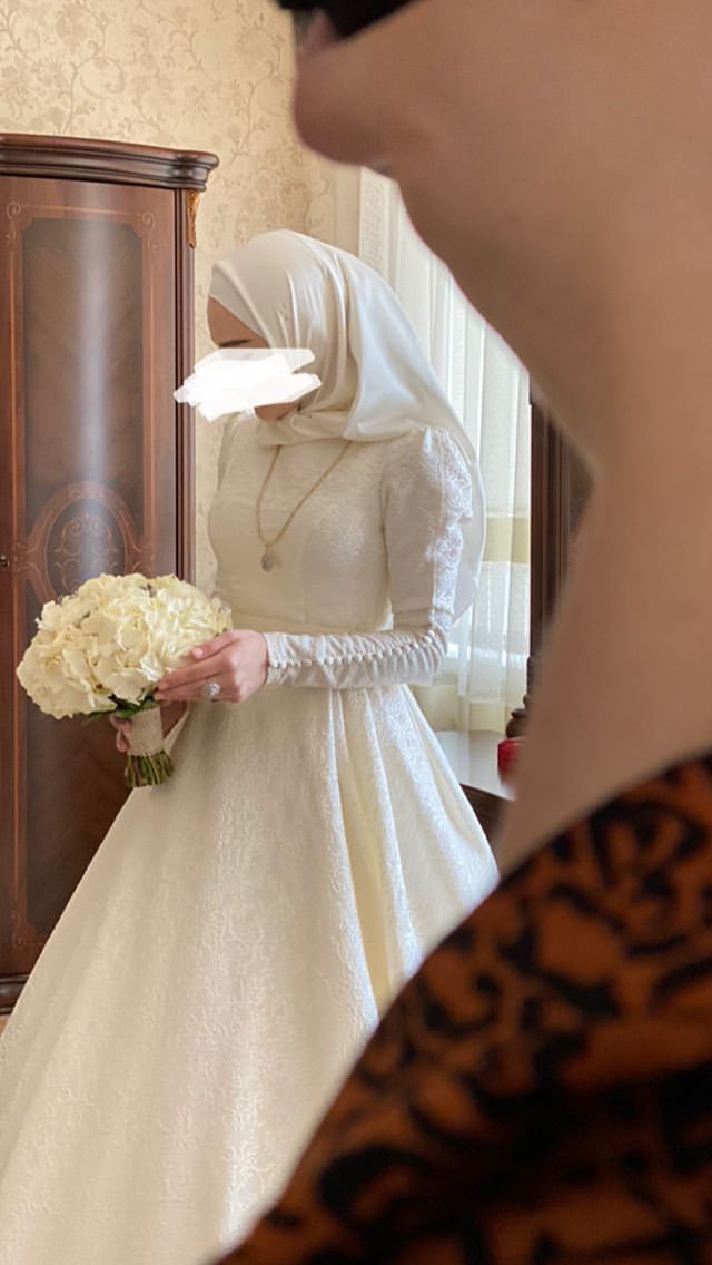 a woman in a wedding dress is looking at herself in the mirror while holding a bouquet