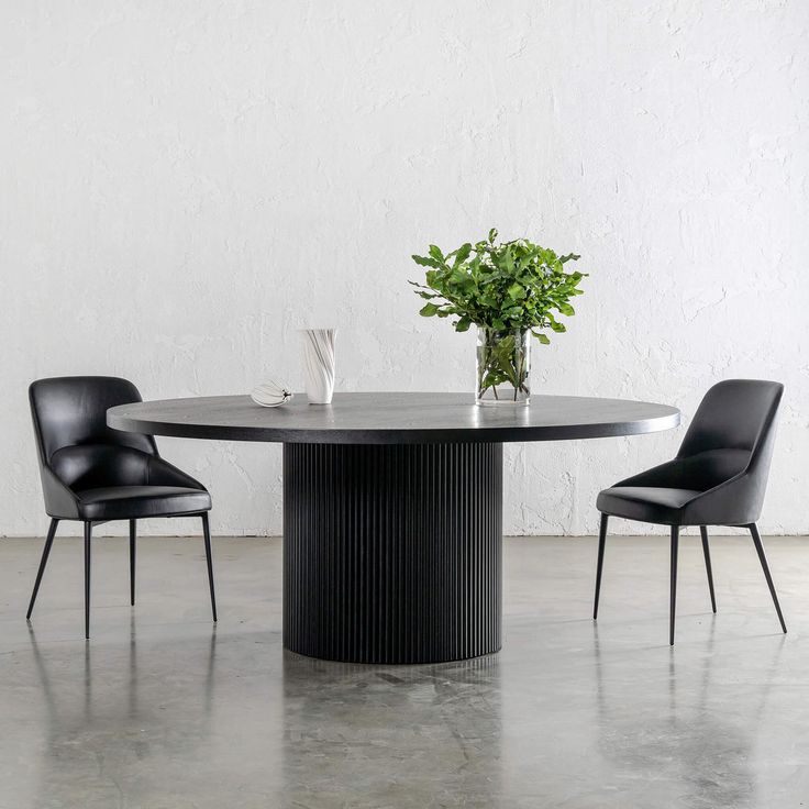 a round table with chairs around it and a plant in the center on one side