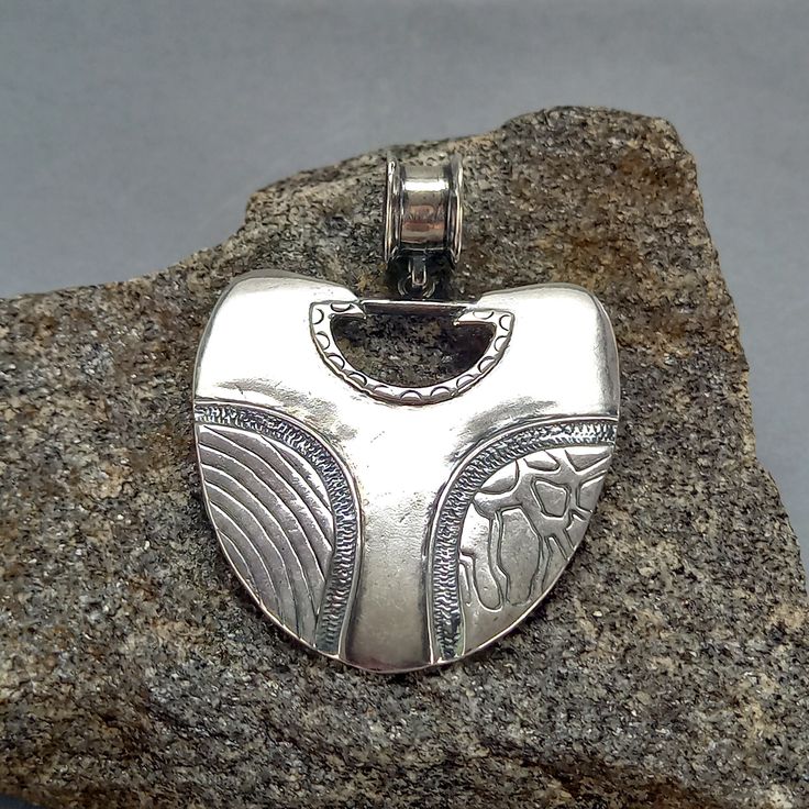 A unique handcrafted necklace made of 925 sterling silver, featuring a boho hippie pendant with a geometric ethnic tribal design. This artisan jewelry piece is truly one of a kind, perfect for those who appreciate distinctive and elegant accessories. * 100% polished solid sterling silver * .925 trademark stamp Sterling  Silver * Solid sterling silver weight: approx. 7.5 Grams * Length: 60 mm  / 2.36 inches  *  Width: 45 mm  / 1.77 inches * Inner Bail diameter: 10 mm / 0.38 inches * Solid sterlin Artisan Silver Heart Pendant Necklace, Artisan Sterling Silver Necklace For Festival, Artisan Silver Engraved Necklaces, Bohemian Sterling Silver Engraved Necklaces, Sterling Silver Amulet Jewelry For Festival, Sterling Silver Necklace With Large Pendant For Festival, Unique Antique Silver Pendant Jewelry, Bohemian Antique Silver Pendant Jewelry, Artisan Silver Necklace Stamped 925