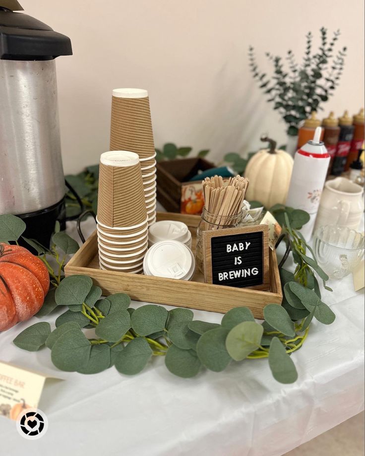 there is a tray with paper cups and plates on it, along with greenery