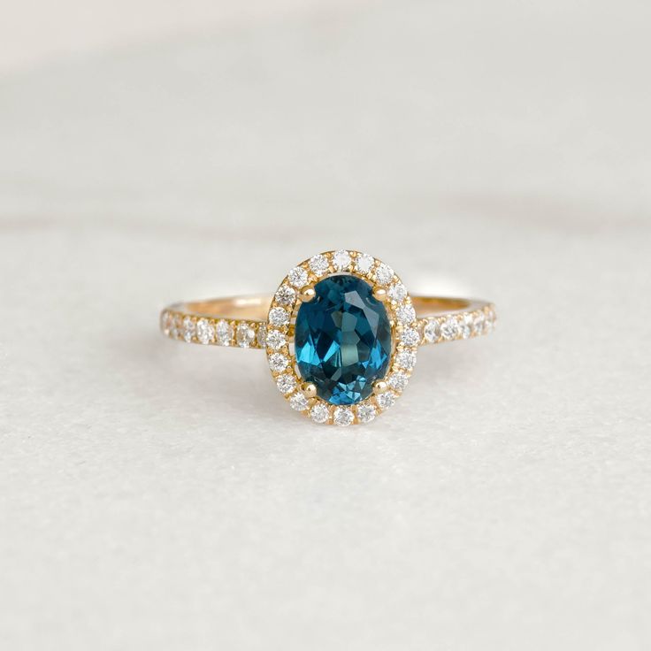 a ring with a blue stone surrounded by white and yellow diamonds on a plain surface