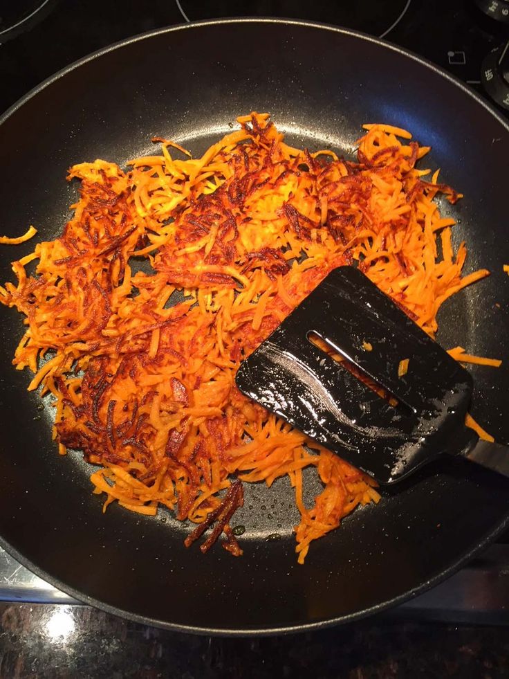 shredded carrots being cooked in a frying pan