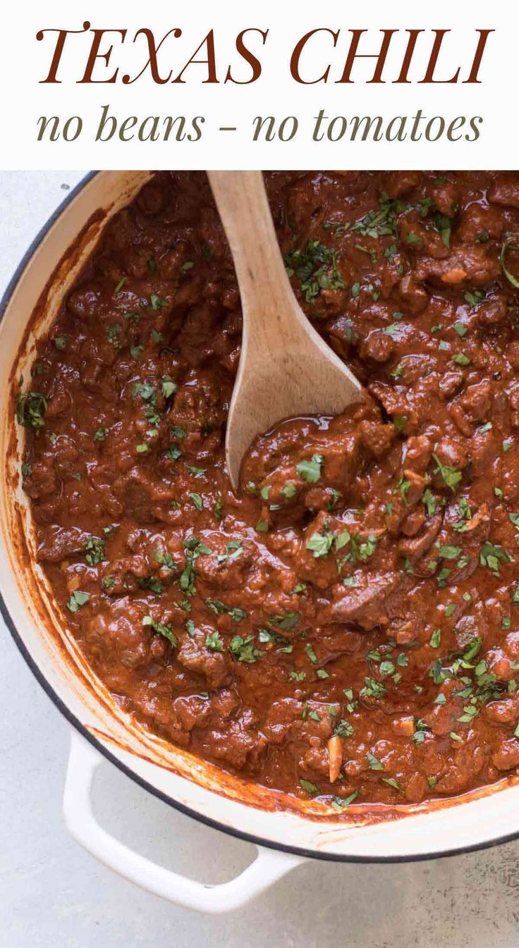 a wooden spoon in a pot filled with chili