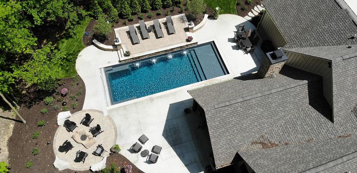 an aerial view of a house with a pool in the yard and lounge chairs around it