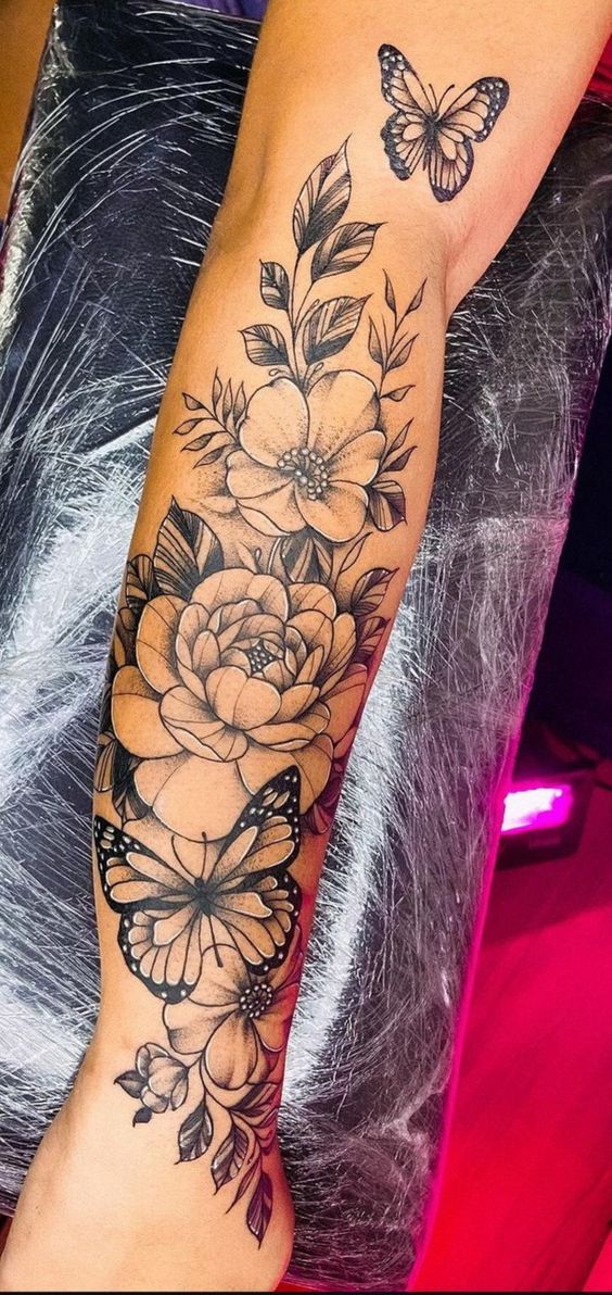 a woman's arm with flowers and butterflies on it