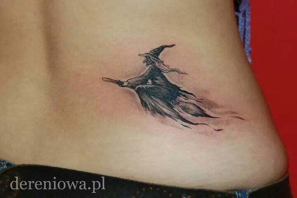 a woman's back with a tattoo of a witch flying through the air