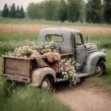 an old truck with flowers in the back is parked on a dirt road near a field