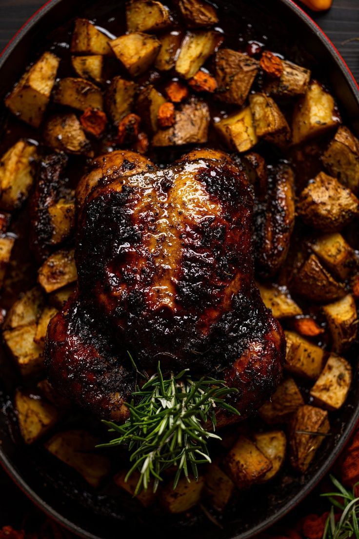 a roasted turkey and potatoes in a pan with rosemary garnish on the side