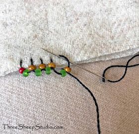 a pair of knitting needles sitting on top of a piece of white fabric next to some beads