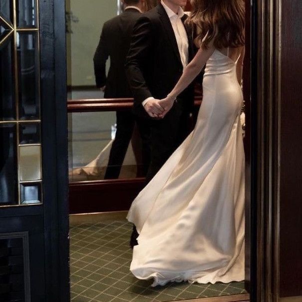 a man and woman standing in front of a doorway holding hands while looking at each other