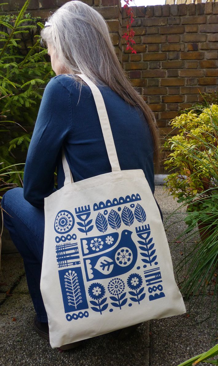 a woman sitting on the ground with a tote bag in front of her back