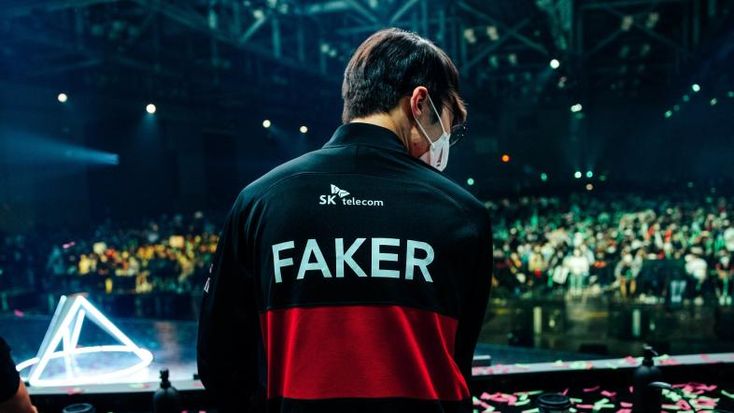 a man standing in front of a crowd wearing a black and red shirt with the word faker on it