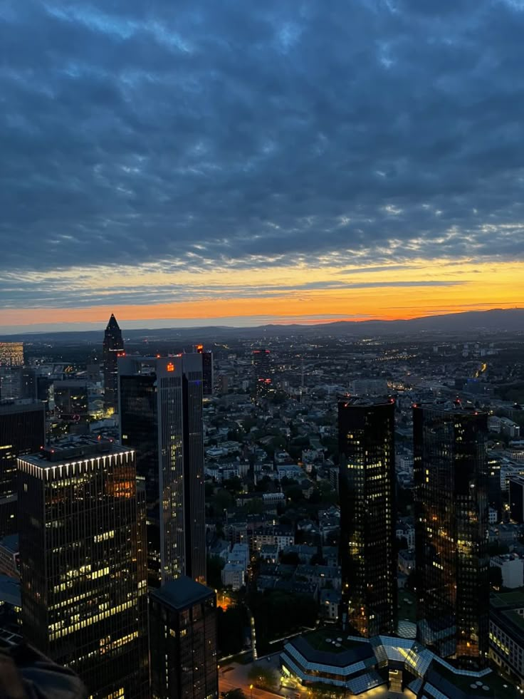 the city skyline is lit up at night, with clouds in the sky above it