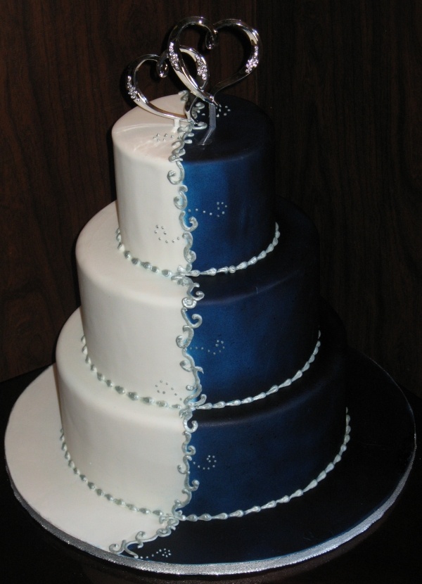 a blue and white wedding cake with two hearts on top