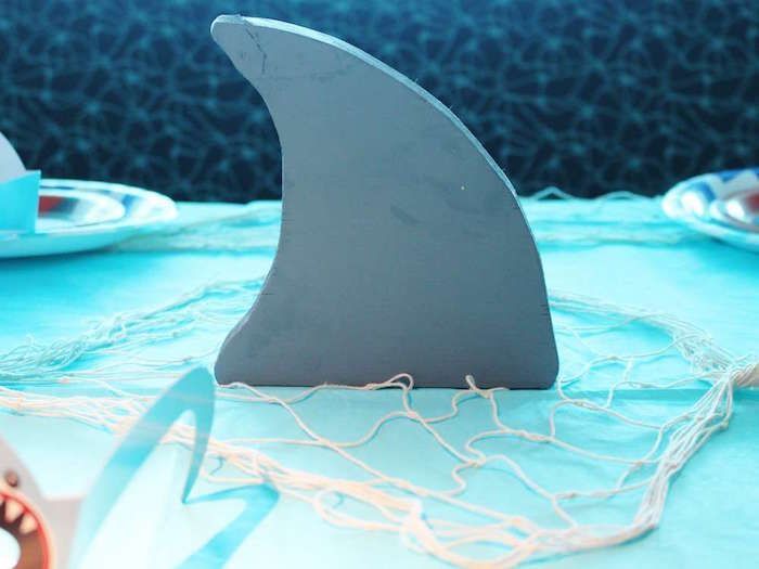 a shark fin sculpture sitting on top of a table next to other plates and utensils