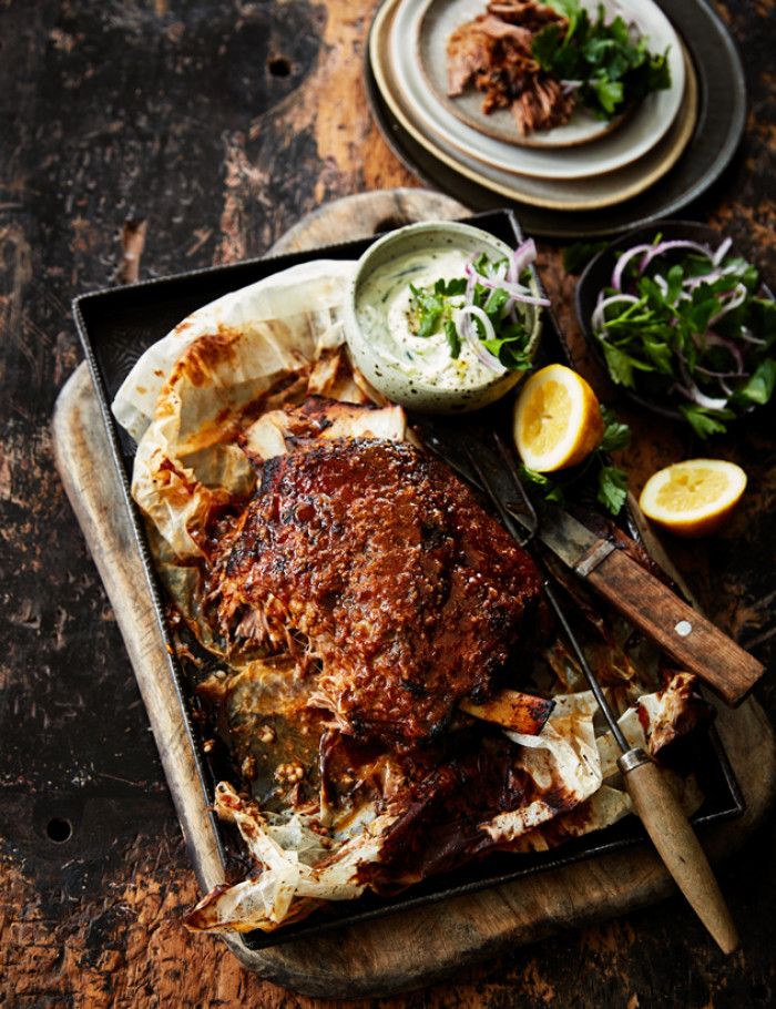 a roasting pan filled with meat, vegetables and sauces on a wooden table