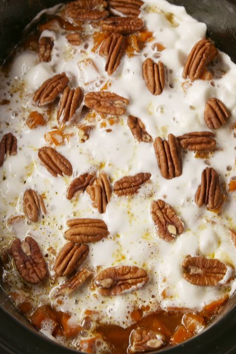 the food is being cooked in the crock pot with white sauce and pecans