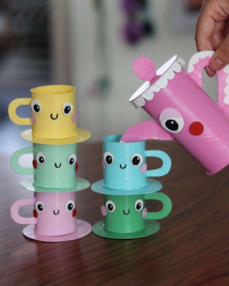 a person is holding a cup and some cups on a table