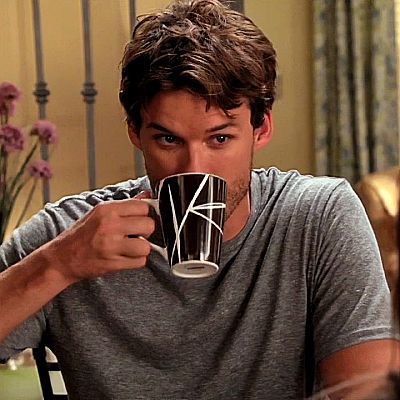 a man sitting at a table drinking from a coffee cup in front of his face