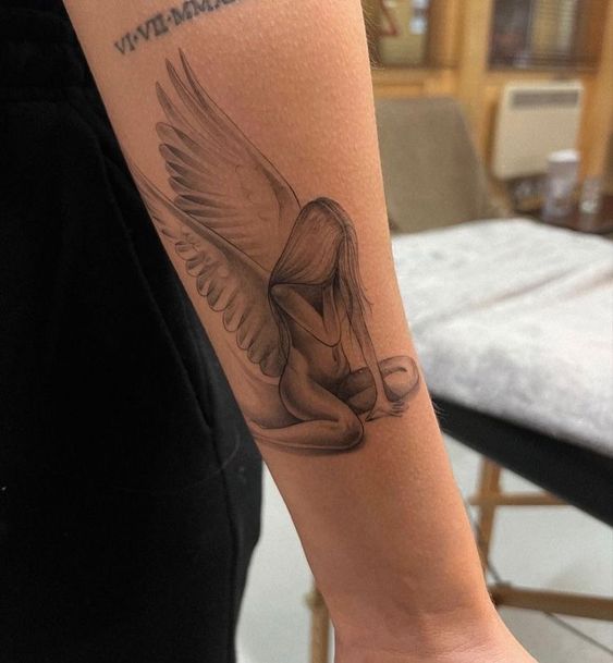 a woman's arm with a tattoo on it that has an angel sitting on the ground