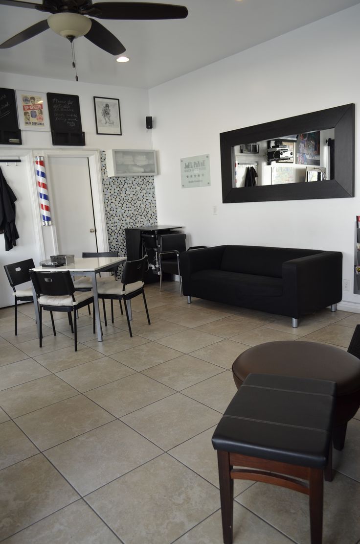 a living room filled with black furniture and a white wall mounted clock above the fireplace