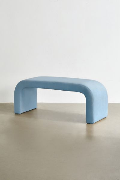 a blue bench sitting on top of a cement floor in front of a white wall