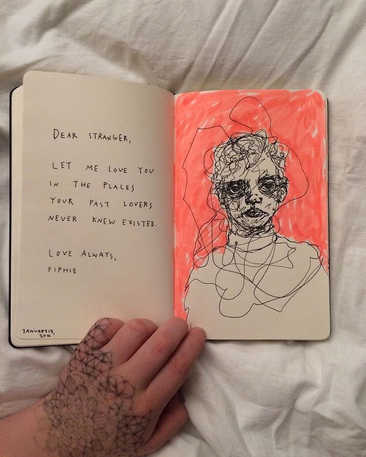 a hand holding an open book with a drawing on the cover and writing in it