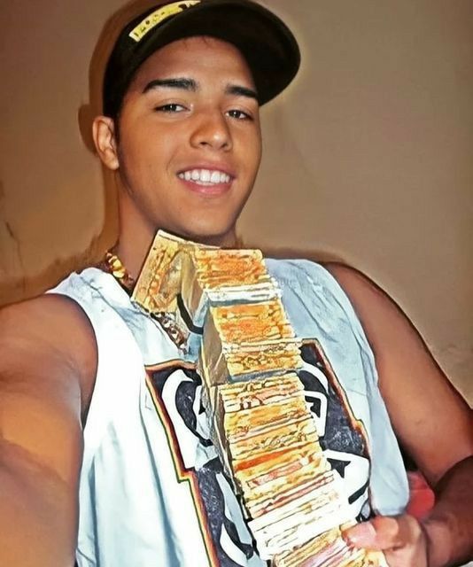 a young man wearing a baseball cap and holding a stack of money