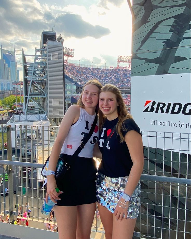 two girls standing next to each other in front of a stadium